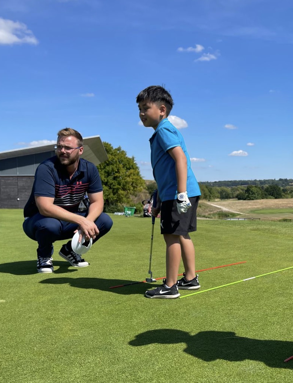 A young golfer putting with our pro